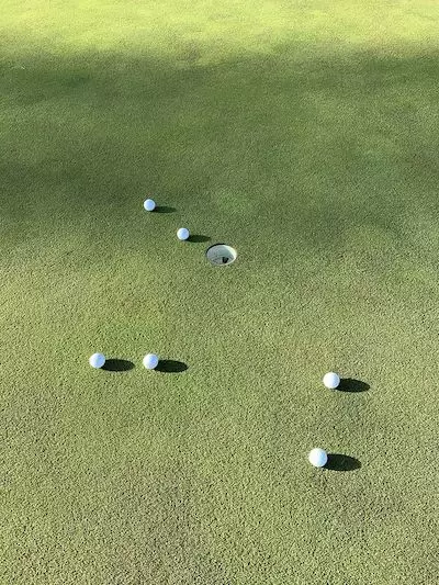 ゴルフボールをスチールシャフトのパターで2球ずつ打って差を確認している画像です