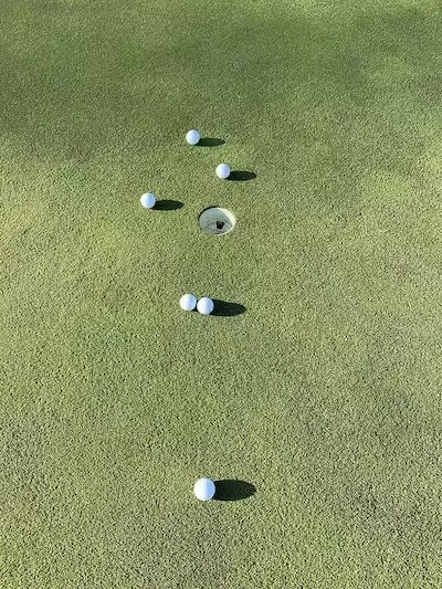 ゴルフボールをカーボンシャフトのパターで2球ずつ打って差を確認している画像です