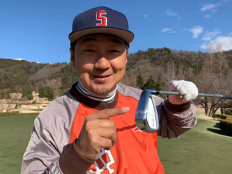 野村タケオの自画像写真,8番アイアンを持っている