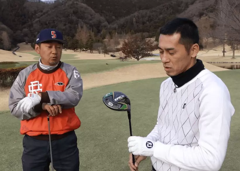 ゴルフ場で野村タケオと佐藤順がクラブを持って話をしている写真