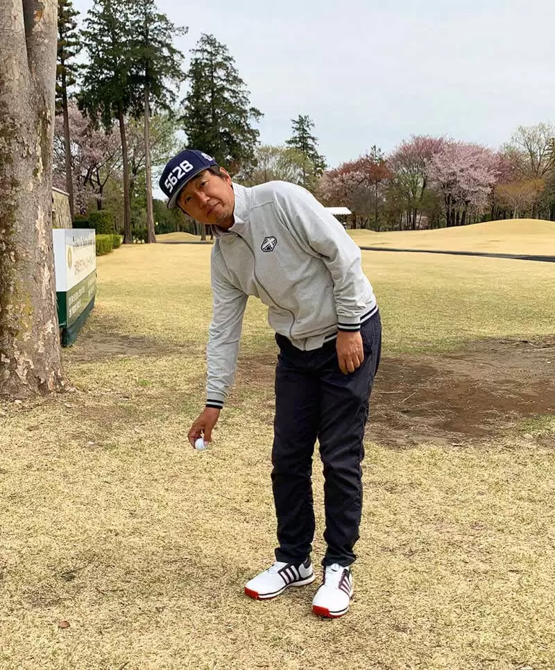 ゴルフ場で野村タケオが膝下からドロップをしようとしている写真