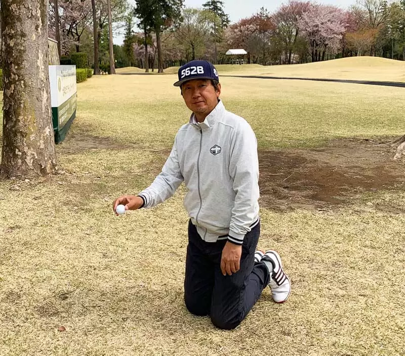 ゴルフ場で野村タケオが両ひざをついてドロップしようとする写真
