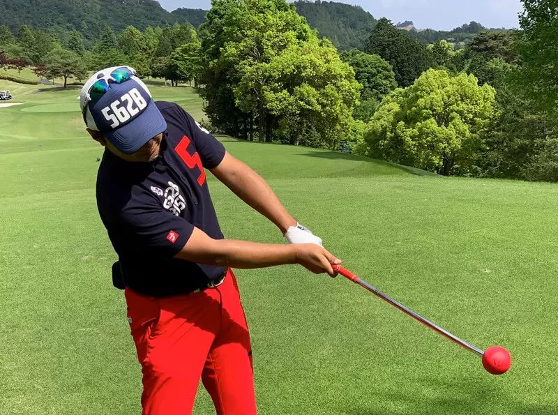 ゴルフ場でフレループを持ってスイングしている写真