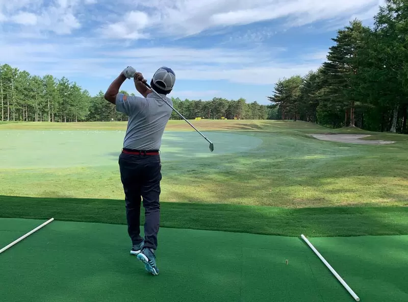 ゴルフ場で野村タケオが打っている後ろ姿の写真