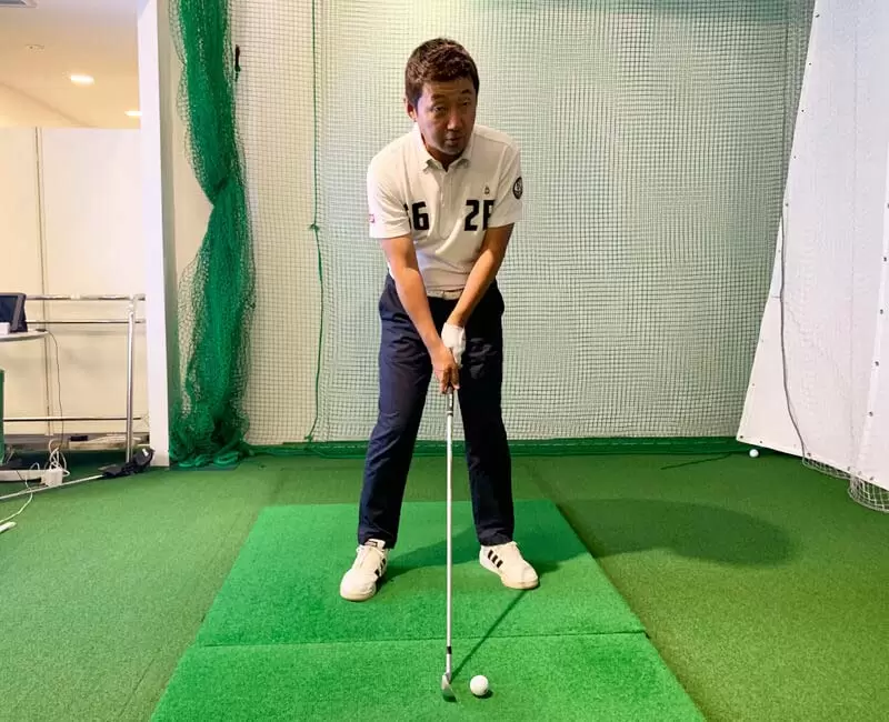 野村タケオがクラブを持って構えている写真