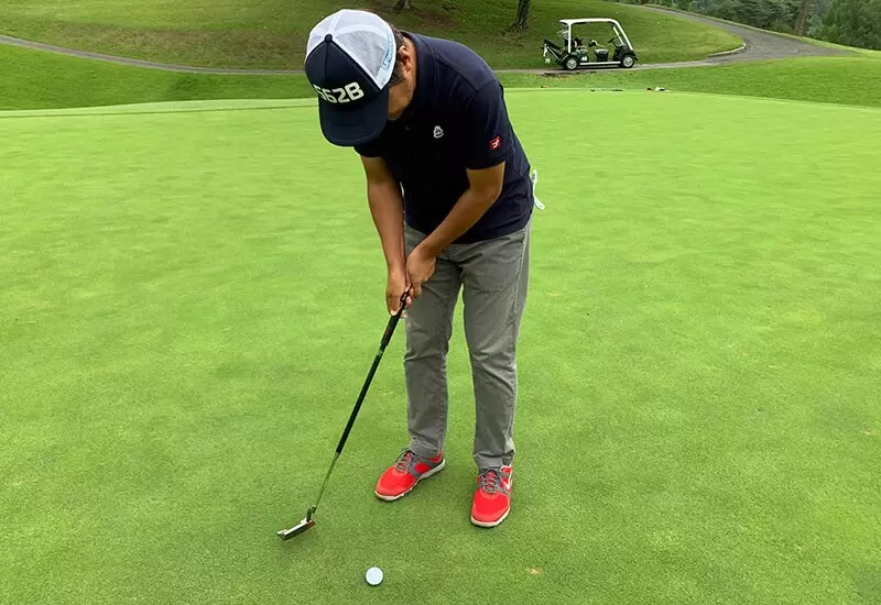 ゴルフ場で野村タケオがパターで打つところの写真
