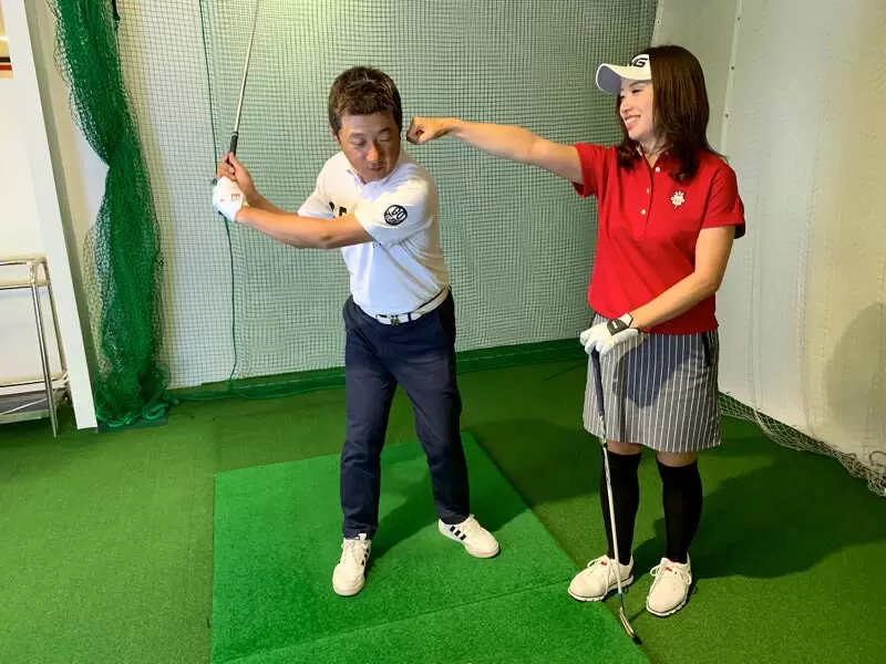 野村タケオが勝又プロから指導を受けている写真,トップから振り下ろす姿