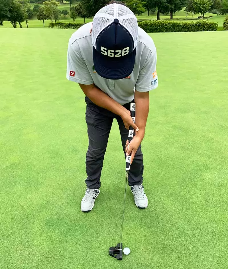 ゴルフ場で野村タケオがパターを持って構えている写真