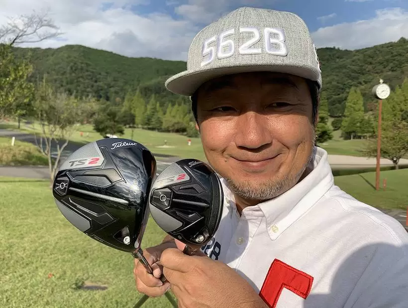 野村タケオがクラブを2本持って立っている写真