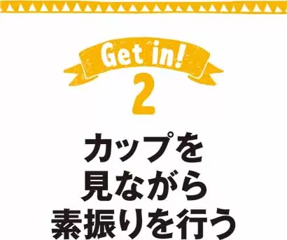カップを見ながら素振りを行う