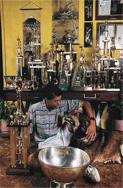 少年時代にトロフィーが飾られた自宅居間で愛犬ジェニーと。壁には富士山と金閣寺と思われるタペストリーが。