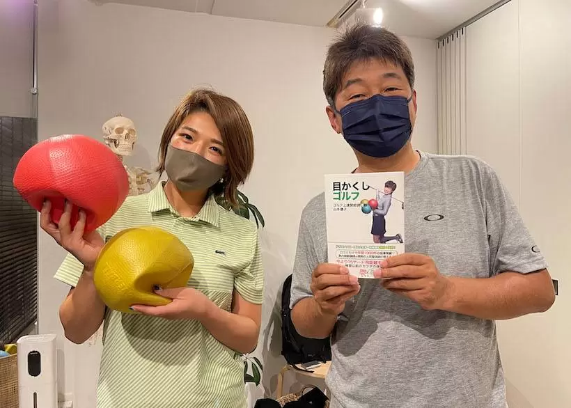 野村タケオが目かくしゴルフという本を持って立っている写真