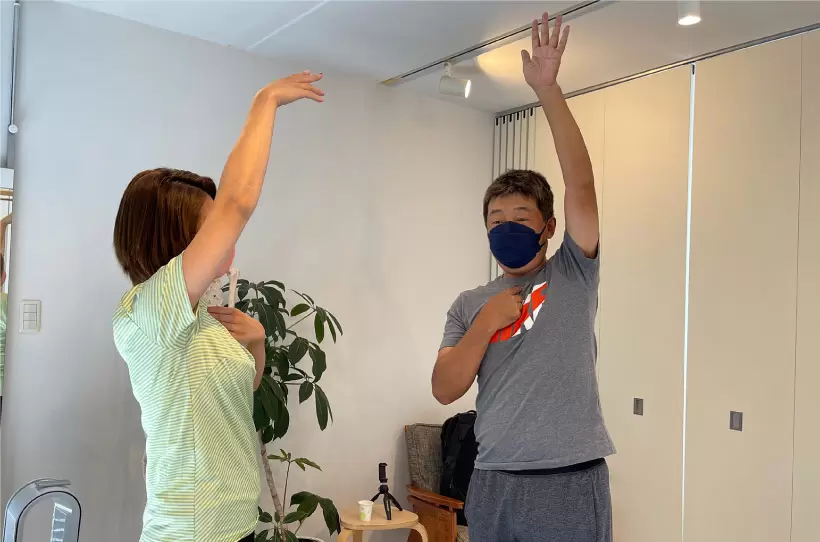 鎖骨の付け根からが腕だと思って手を上に上げてみると、いつもよりも高く上がることを腕を上げて実感している写真