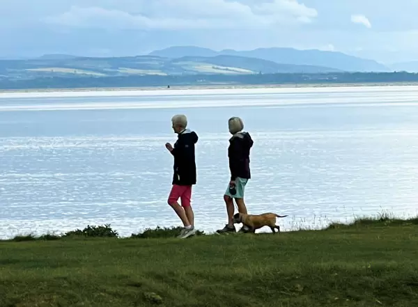 スコットランドのゴルフ場で犬と散歩を楽しむ人々