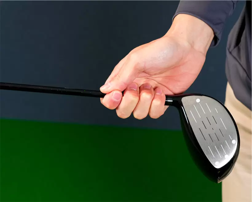 クラブヘッド側のシャフトの部分を右手の指先で引っかけるように持つ。