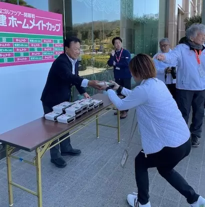 記者やカメラマン一人ひとりに鰻重を手渡しする倉本昌弘副会長